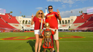 A family standing on the USC football team. Little boy is dressed up in a Trojan costume.