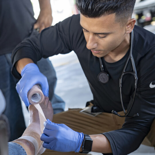 A USC Street Medicine team member wraps the leg of an unhoused person
