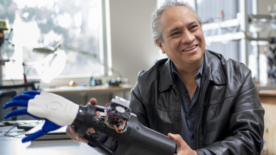 Francisco Valero-Cuevas holding a robotic hand.