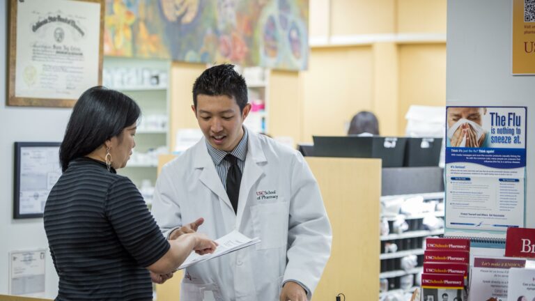 USC School of Pharmacy pharmacist helping a patient with paperwork