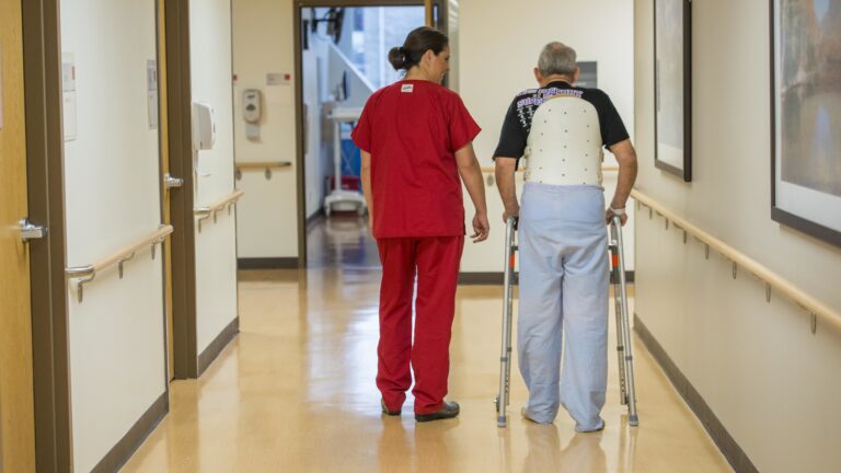 A nurse next to an elderly man with a walker