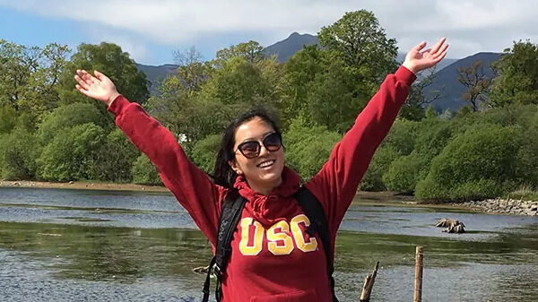 Girl with her hands up in front of a river.