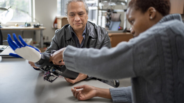Student and Professor examining a robotic arm