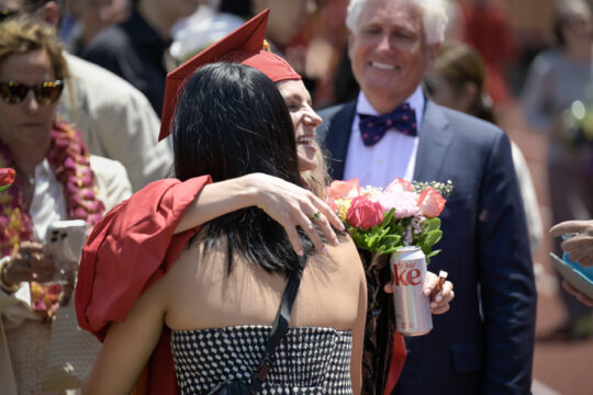 A graduating PhD student hugs a visitor at commencement festivities