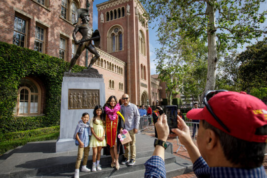 A USC graduate poses in front of Tommy Trojan with her family
