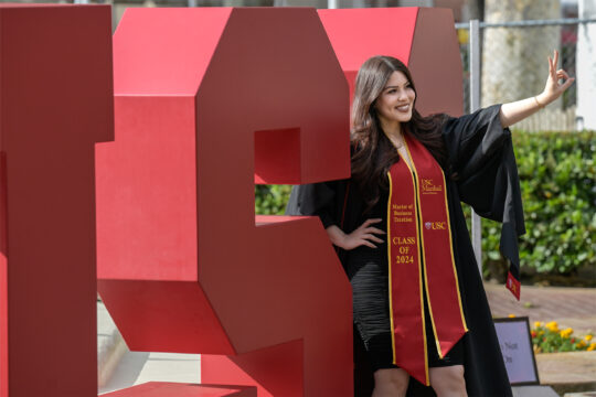 A USC graduate poses in front of a USC sign