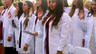 USC Chan students smile for the camera with their white lab coats