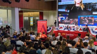 A group of panelists with a crowd of students during an election night watch party at USC Annenberg.