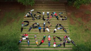 A group of student spell out Aguas Para Avida with their bodies on a lawn