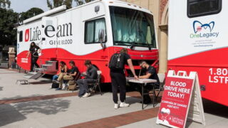 USC students and staff wait outside of a blood drive vans on campus