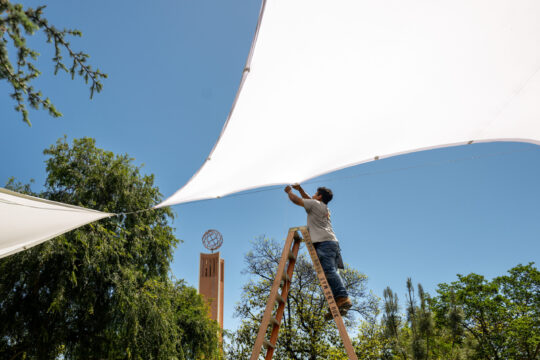 A staffer setup an awnings in Founders Park as preparation for Commencement and graduation events get underway