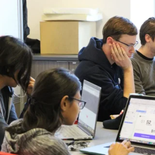 A group of four USC students in front of their laptops in class