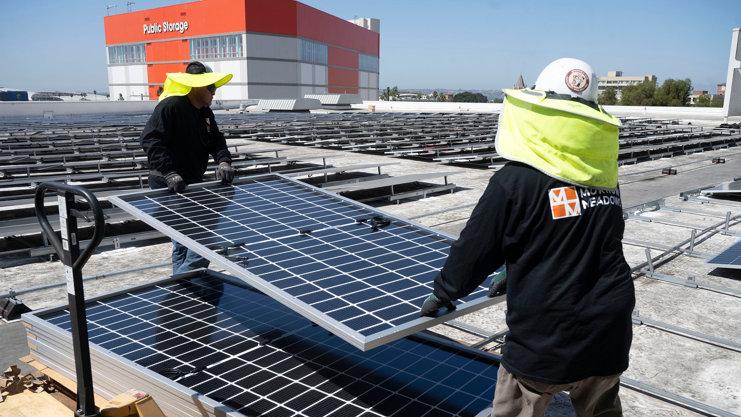 Workers install solar panels on roof of Carole Little Building